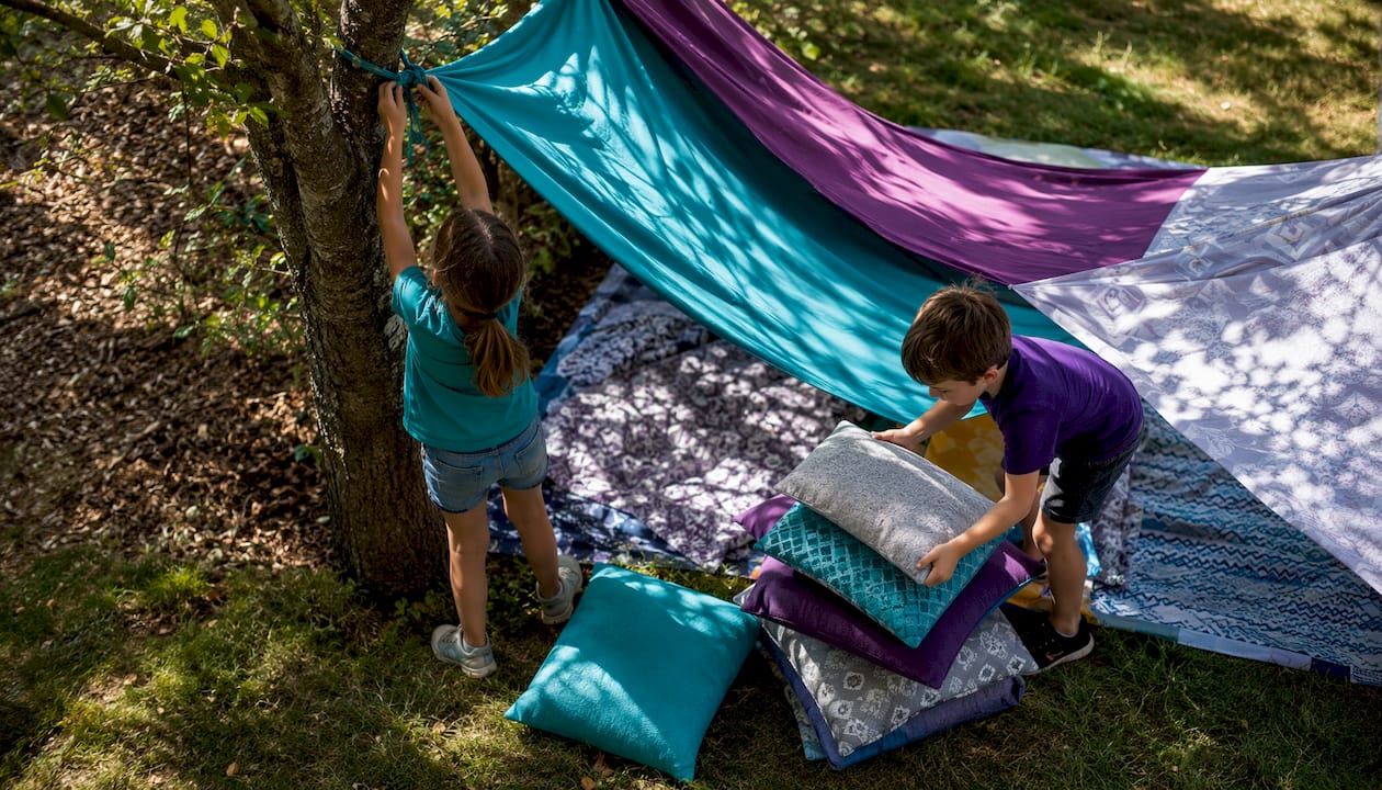 Children building indoor blanket fort