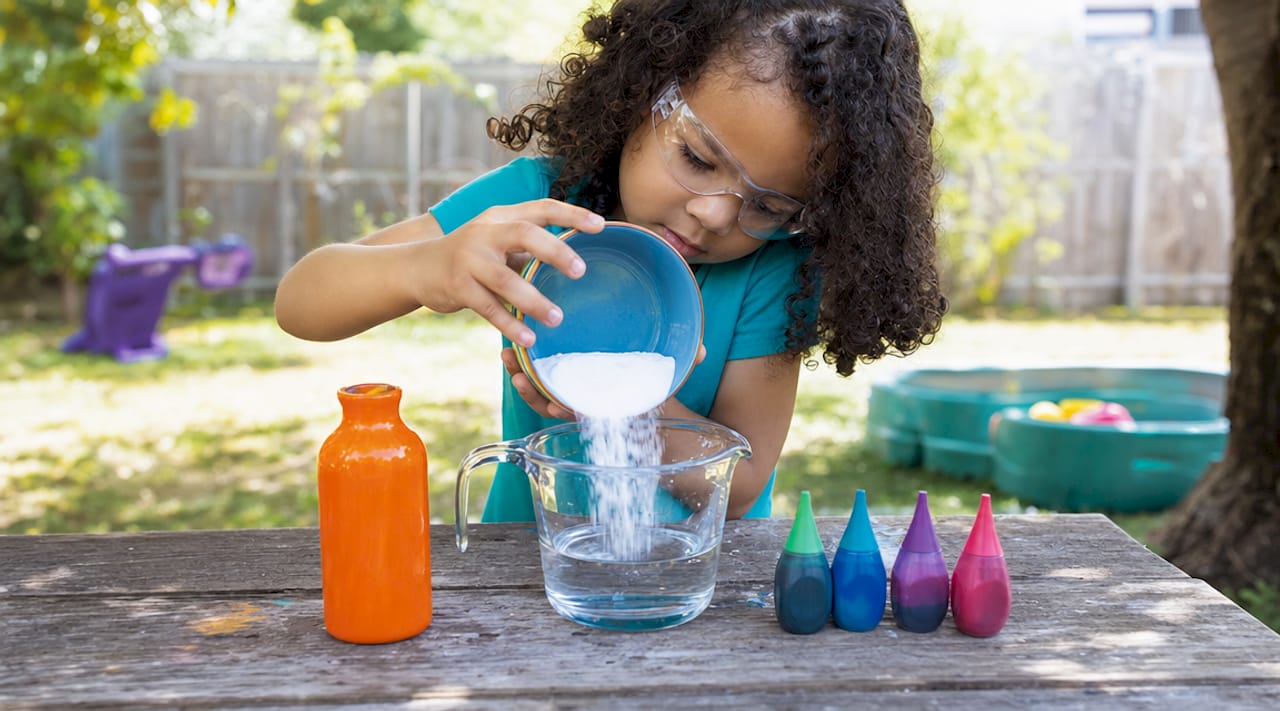 Child preparing baking soda experiment at kitchen counter