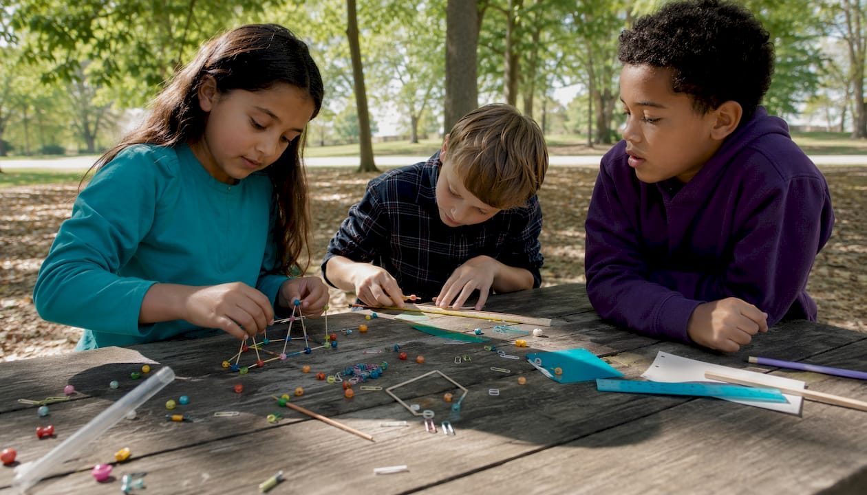 Children assembling STEAM experiment kits at classroom table