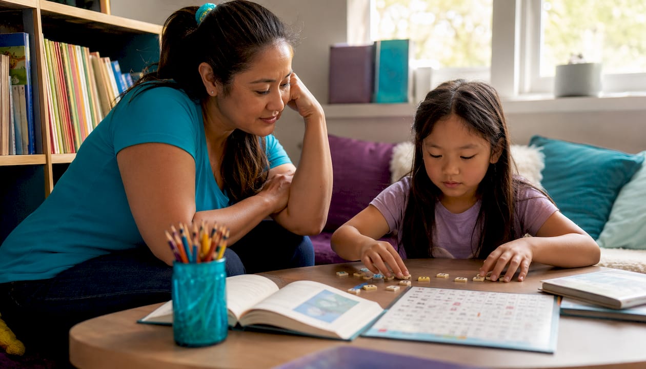 Teacher assisting dyslexic student with letter tiles