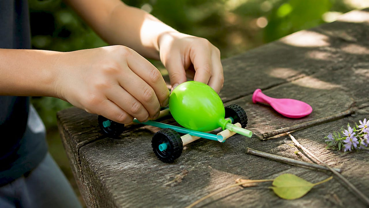 Child hands assembling balloon-powered car